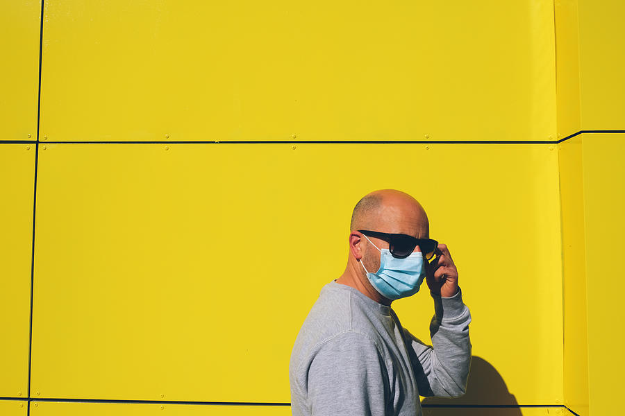 Man wearing a face mask against yellow wall Photograph by Saulgranda