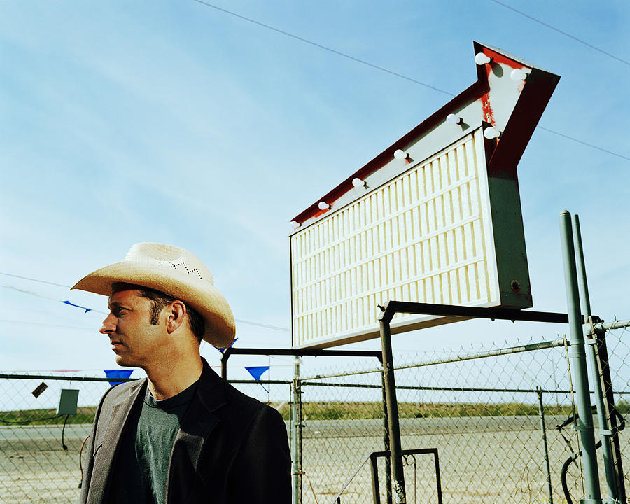 Man wearing cowboy hat by empty billboard, side view Photograph by Andy Ryan