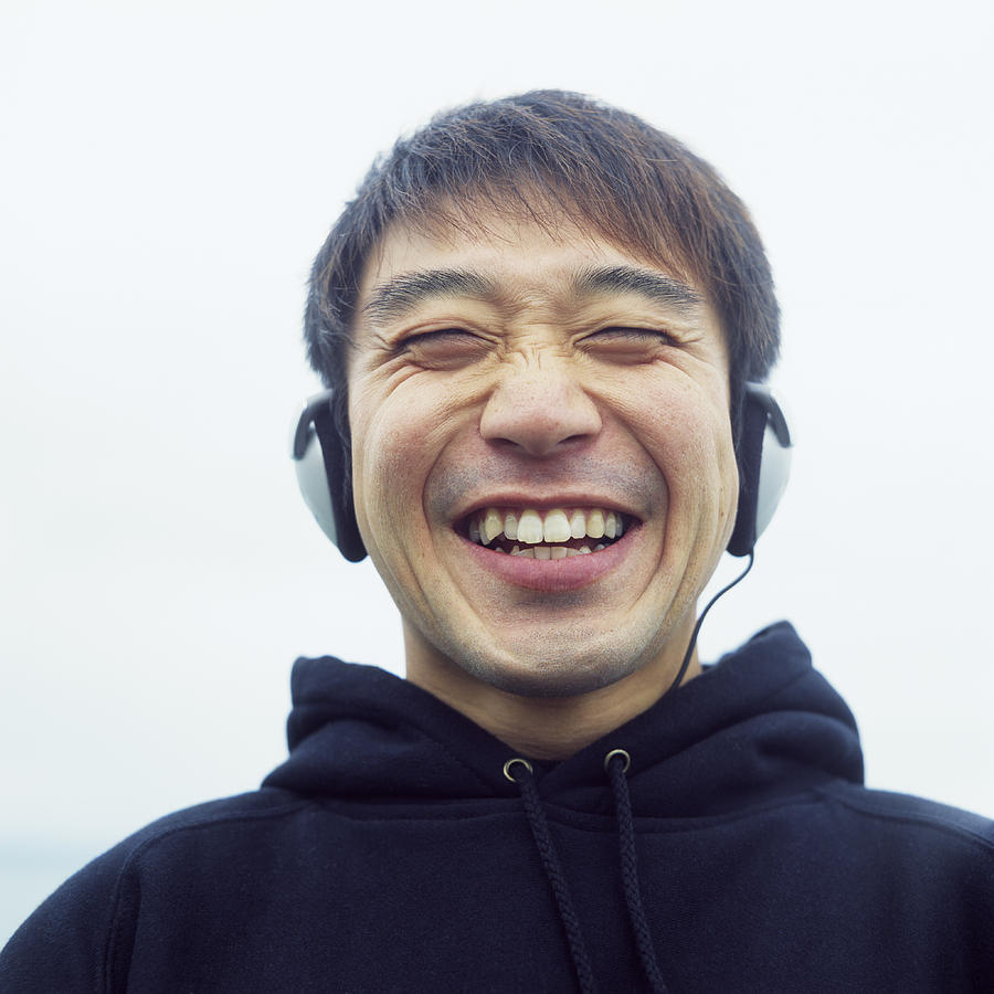 Man wearing headphones, laughing Photograph by Jason Hosking