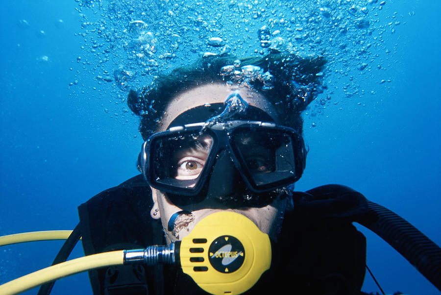 Man wearing scuba mask, underwater view, close-up Photograph by David De Lossy