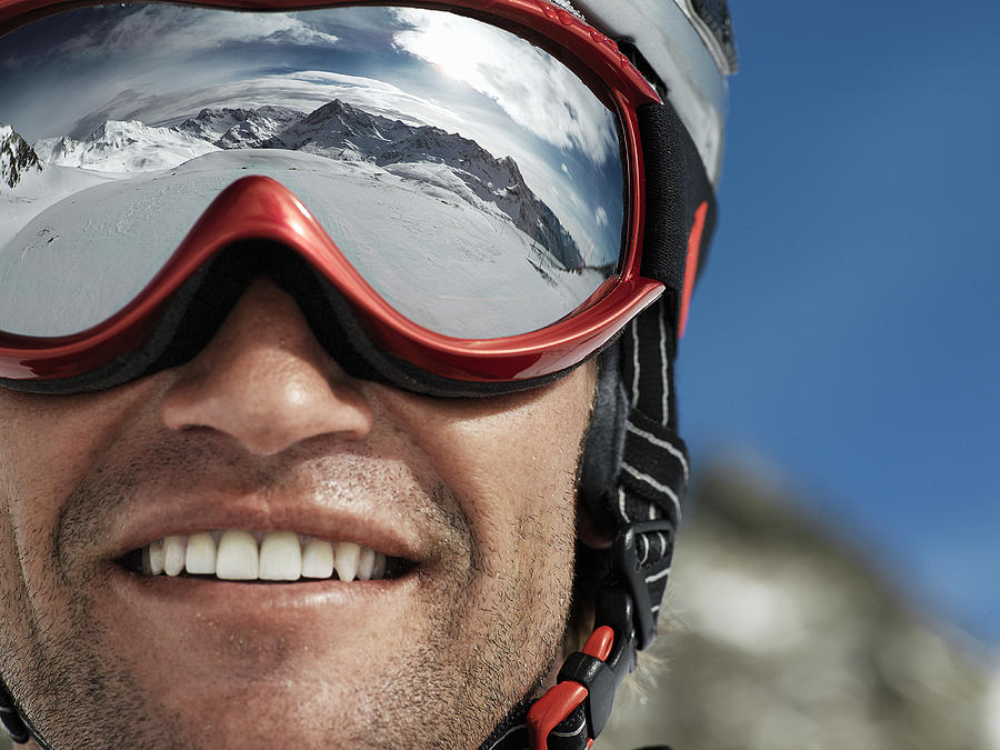 Man wearing ski goggles, smiling, close-up Photograph by David Trood