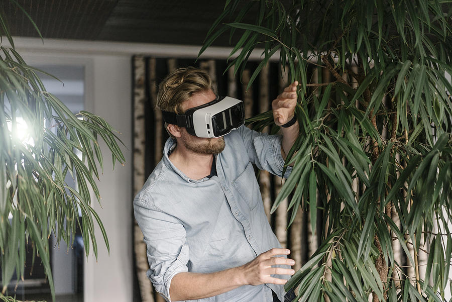 Man wearing VR glasses surrounded by plants Photograph by Westend61
