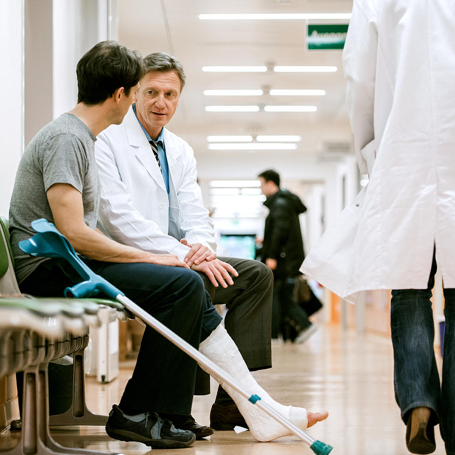 Man With Cruches And Cast On Broken Leg Consulting Doctor Photograph by TommL