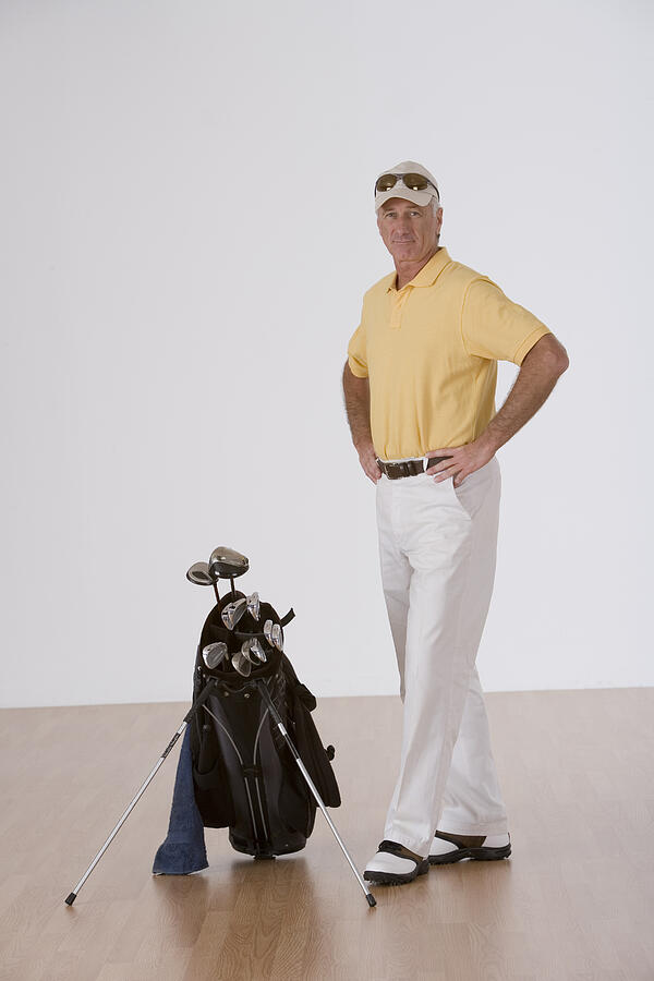Man with golf clubs Photograph by Comstock Images