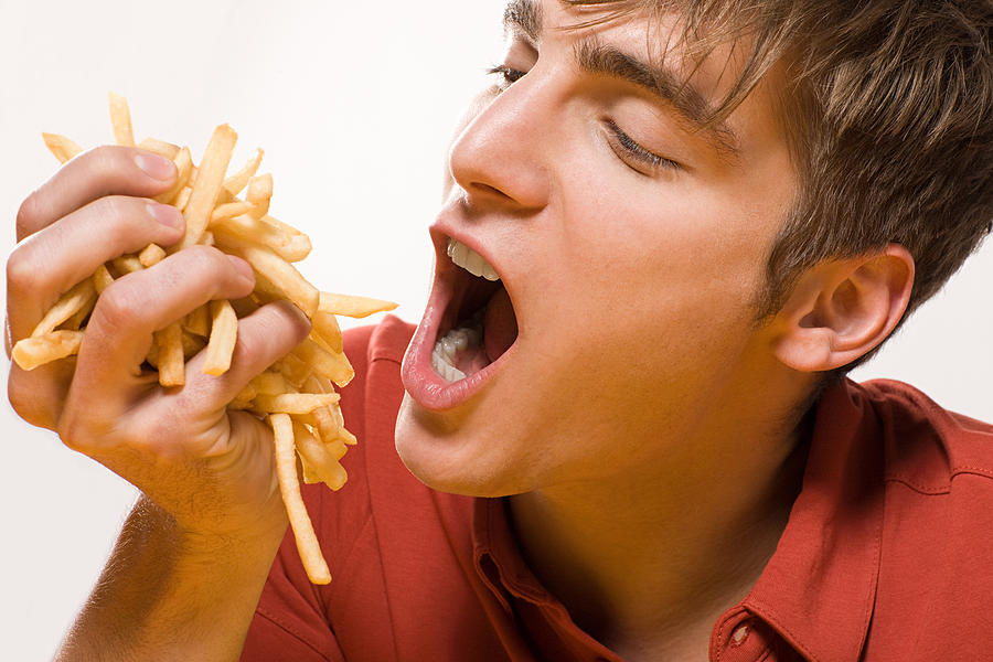 Man with handful of fries Photograph by Image Source