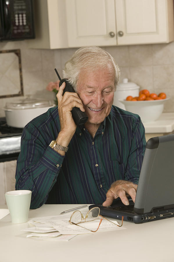 Man with laptop computer and telephone Photograph by Comstock Images