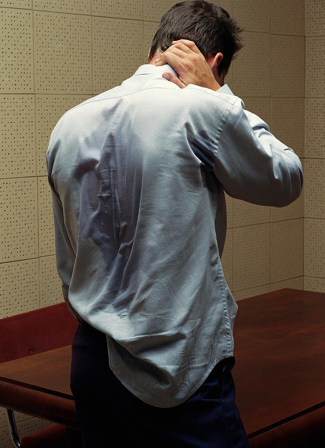 Man with shirt pulled out rubbing back of neck, rear view Photograph by Daniel Day