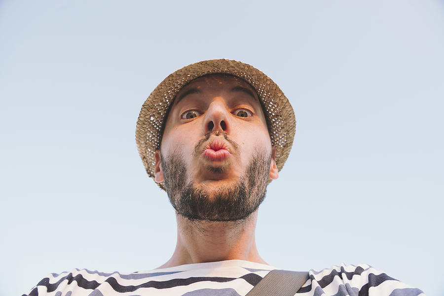 Man with straw hat kissing to the camera Photograph by Westend61
