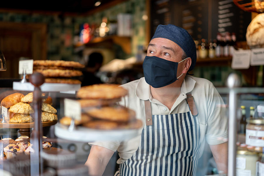Man working at a coffee shop wearing a facemask Photograph by Andresr