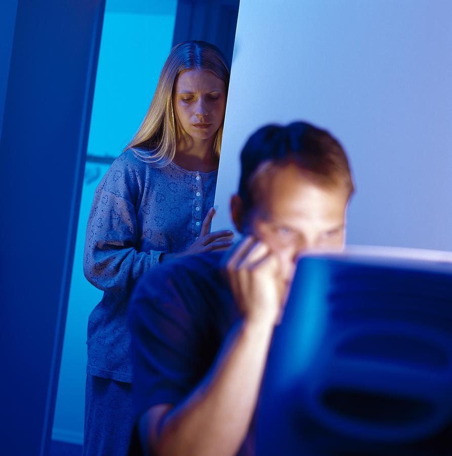 Man working at computer with sad woman in background Photograph by Design Pics/Ron Nickel