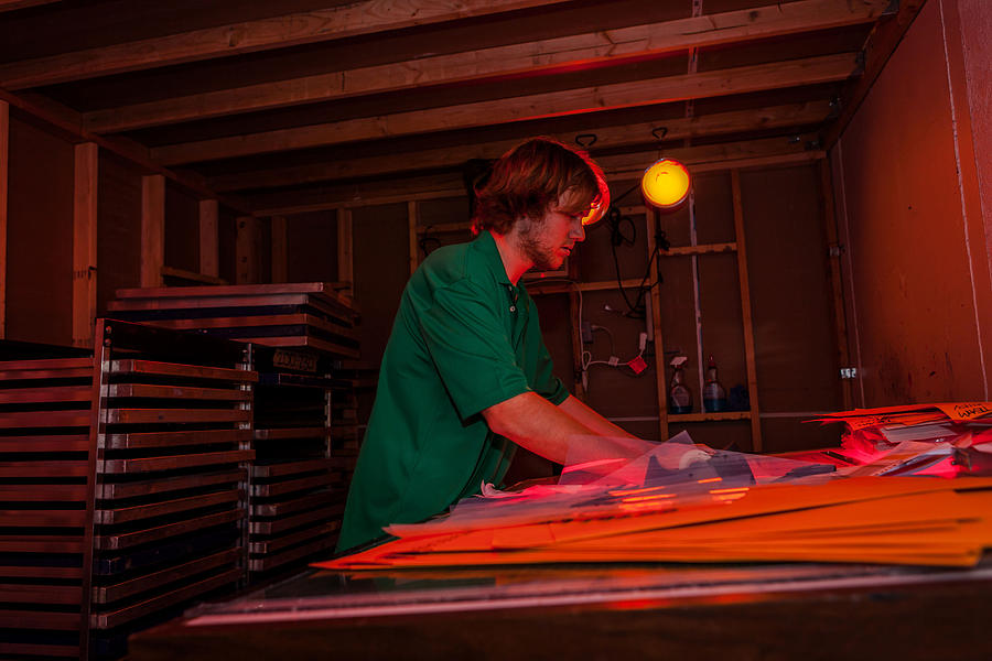 Man working in darkroom in screen printing workshop Photograph by Heshphoto