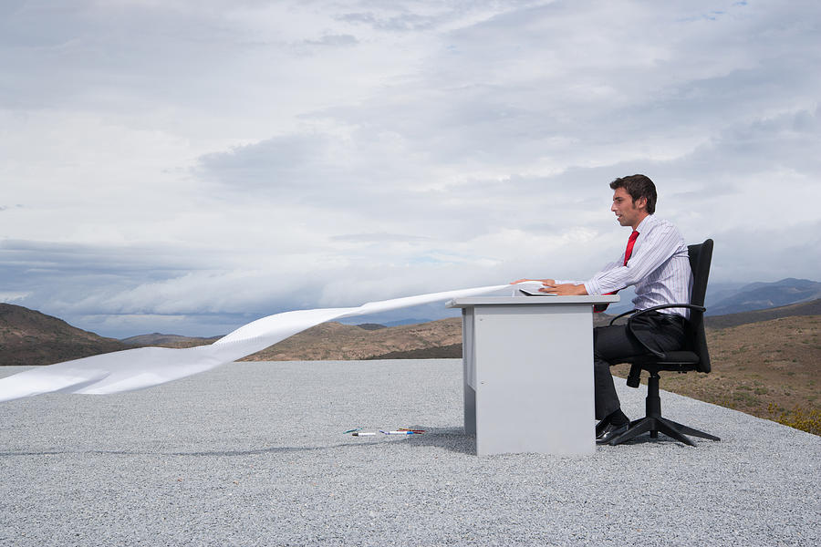 Man working outdoors with papers blowing in the wind Photograph by Martin Barraud