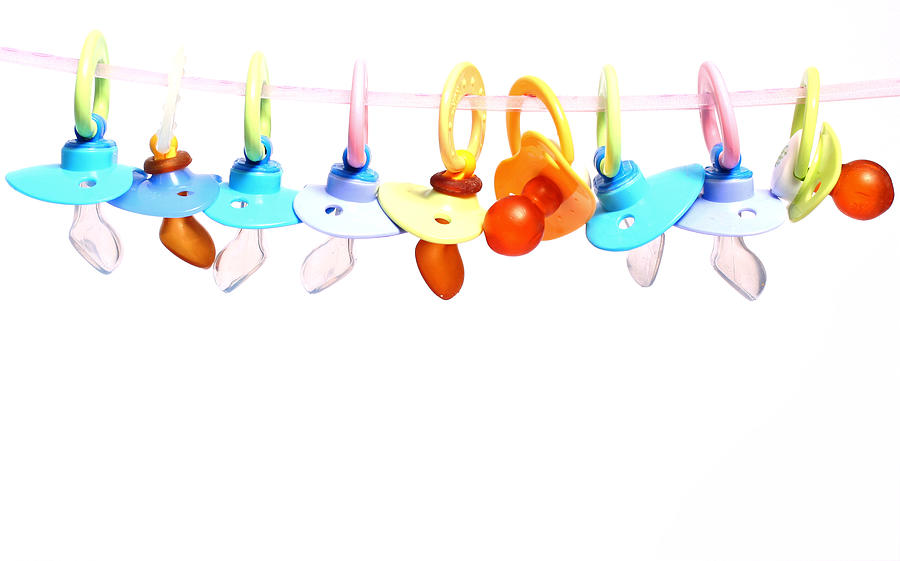 Many baby pacifiers hanging from a string Photograph by YsaL