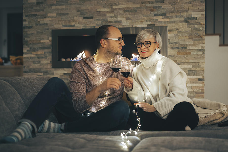 Married couple celebrating new years eve in the comfort of home with a glass of wine Photograph by Ziga Plahutar
