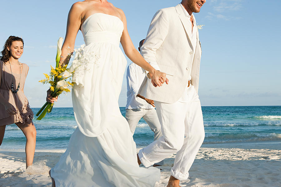 Married couple on beach with friends Photograph by Image Source