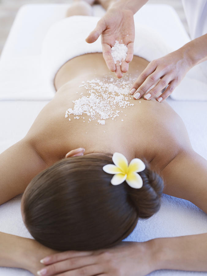 Masseuse applying massage salts to a womans back Photograph by OJO Images