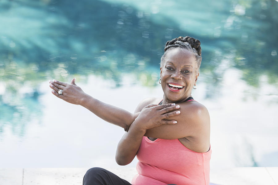 Mature African American woman stretching by pool Photograph by Kali9