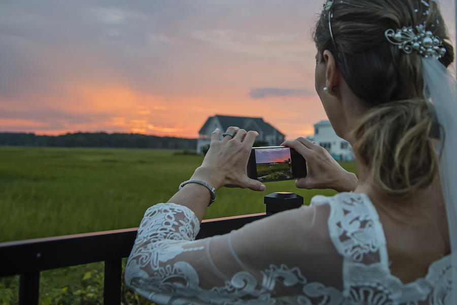 Mature bride photographing sunset in backyard. Photograph by Martinedoucet