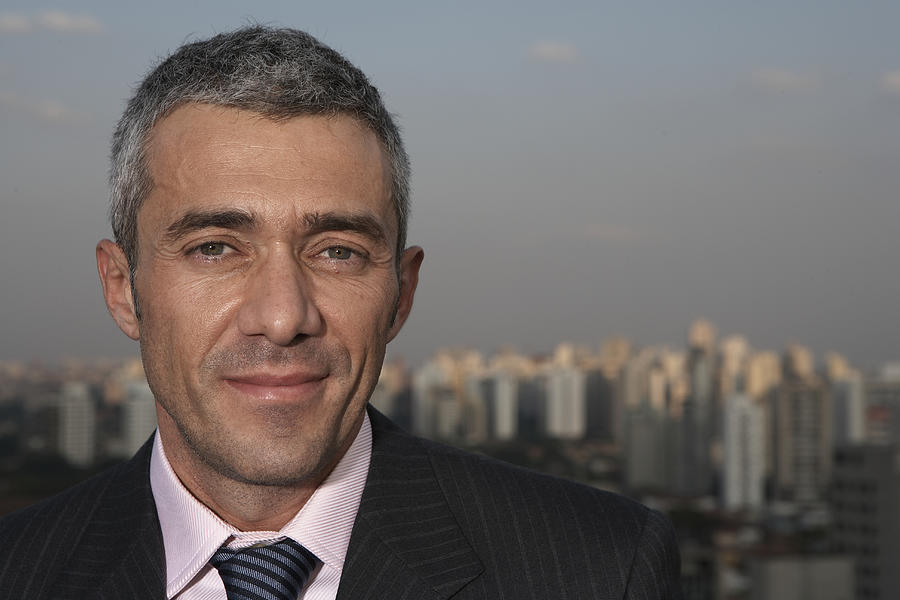 Mature businessman with cityscape in background, portrait Photograph by Thomas Northcut