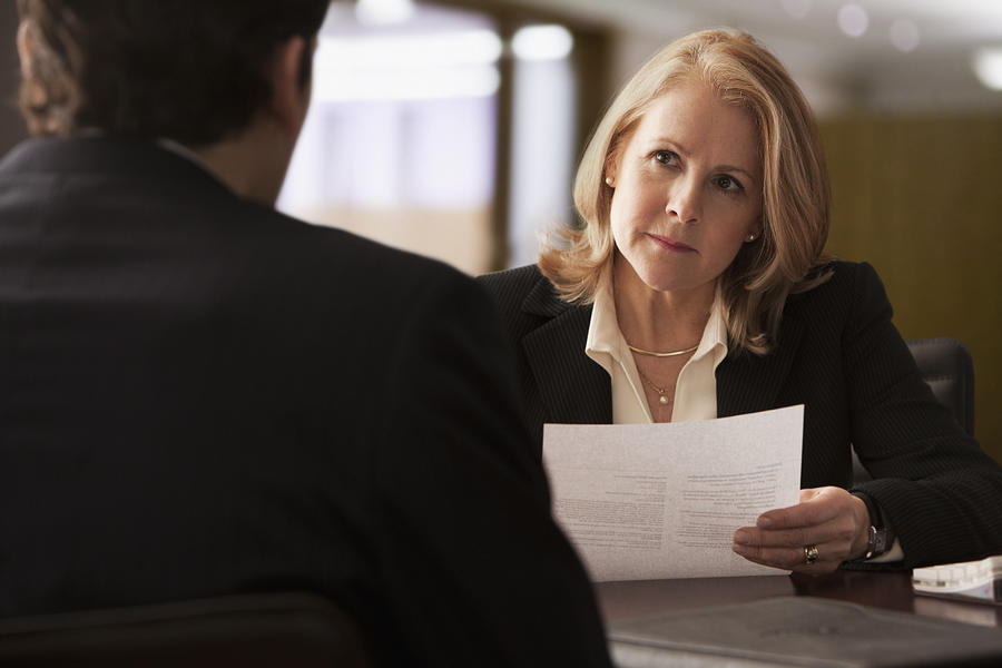 Mature businesswoman interviewing male candidate Photograph by SelectStock