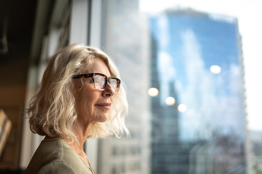 Mature businesswoman looking out of window Photograph by FG Trade
