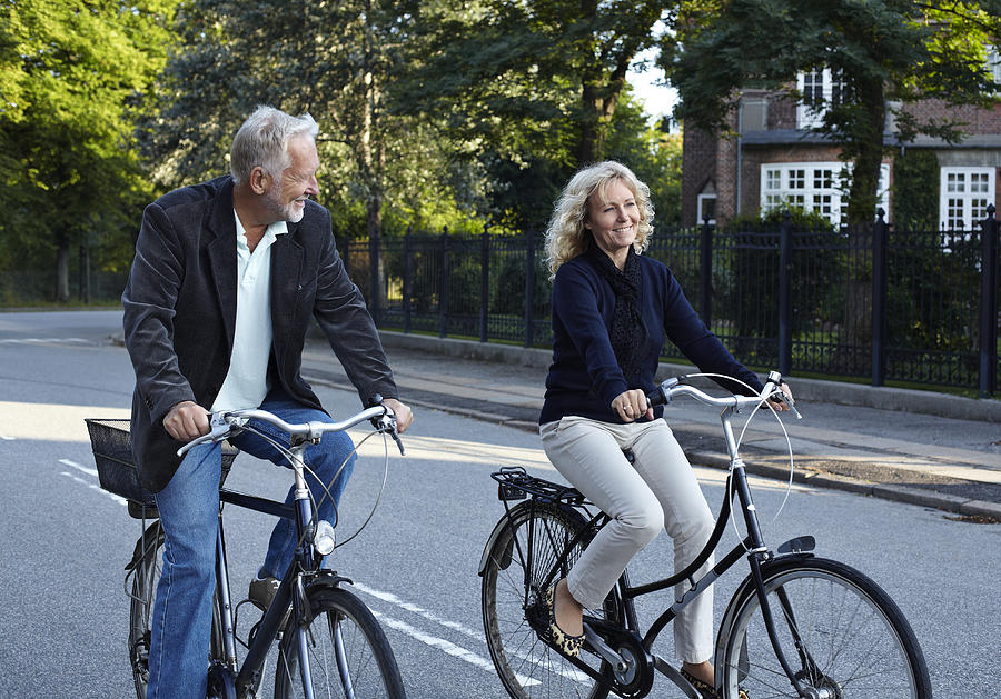 Mature couple cycling in residential neighborhood Photograph by Klaus Vedfelt