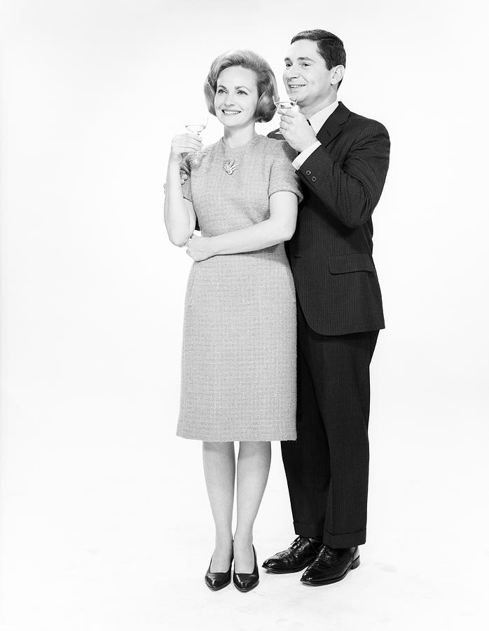 Mature couple drinking cocktails, studio shot Photograph by George Marks
