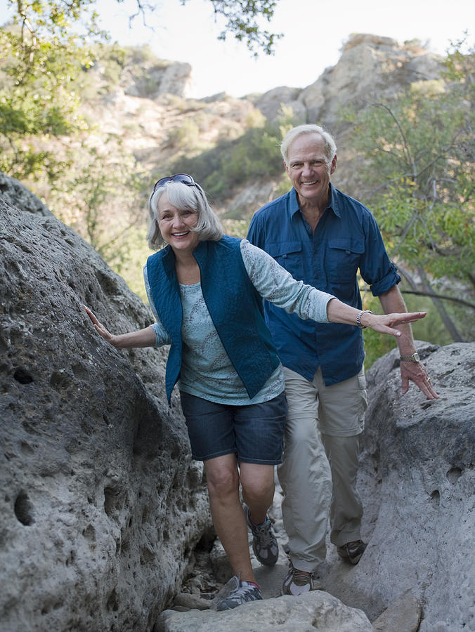 Mature couple hiking through large boulders Photograph by Siri Stafford