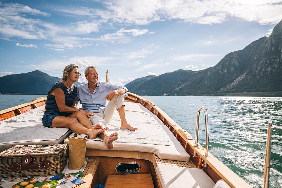 Mature couple relax on sailboat moving through Lake Lugano Photograph by AscentXmedia