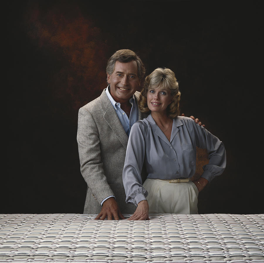 Mature couple standing against black background, smiling, portrait Photograph by Tom Kelley Archive