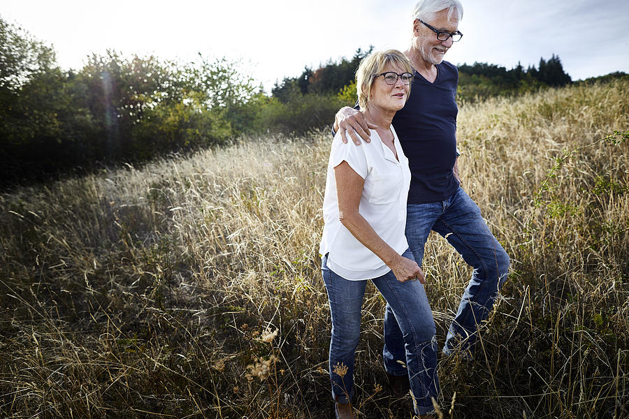 Mature couple walking in a field Photograph by Oliver Rossi