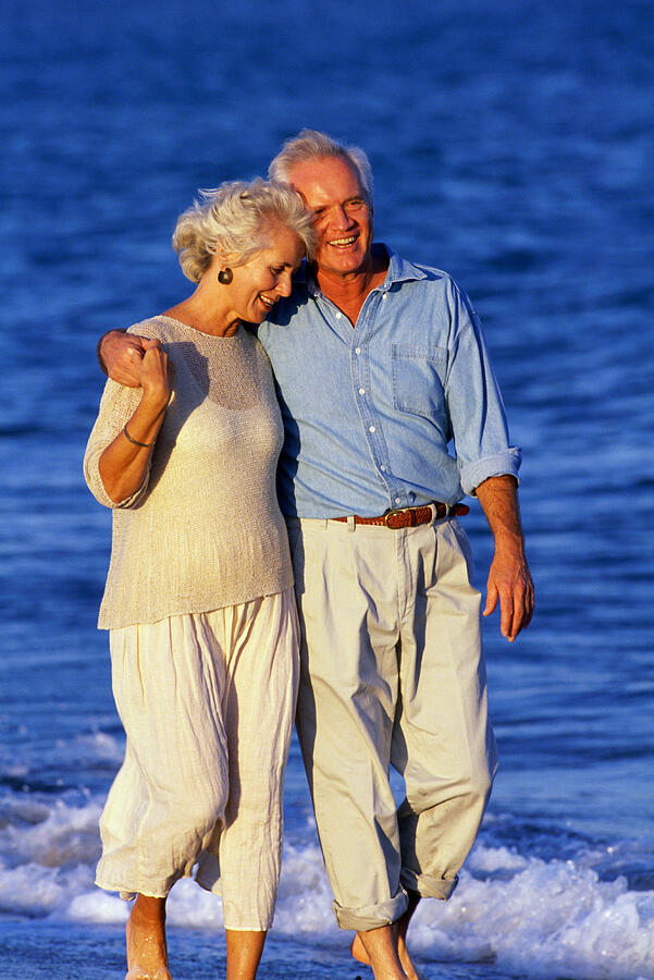 Mature Couple Walking On Beach Photograph by Yellow Dog Productions