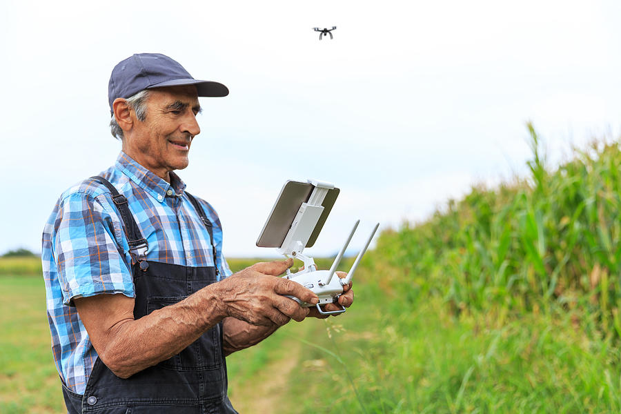 Mature farmer flying a drone over a field Photograph by Valentinrussanov