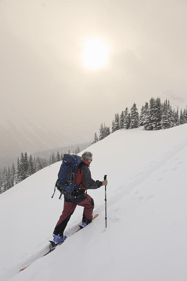 Mature Man Climbing Snowy Mountain On Skis Photograph by Darryl Leniuk