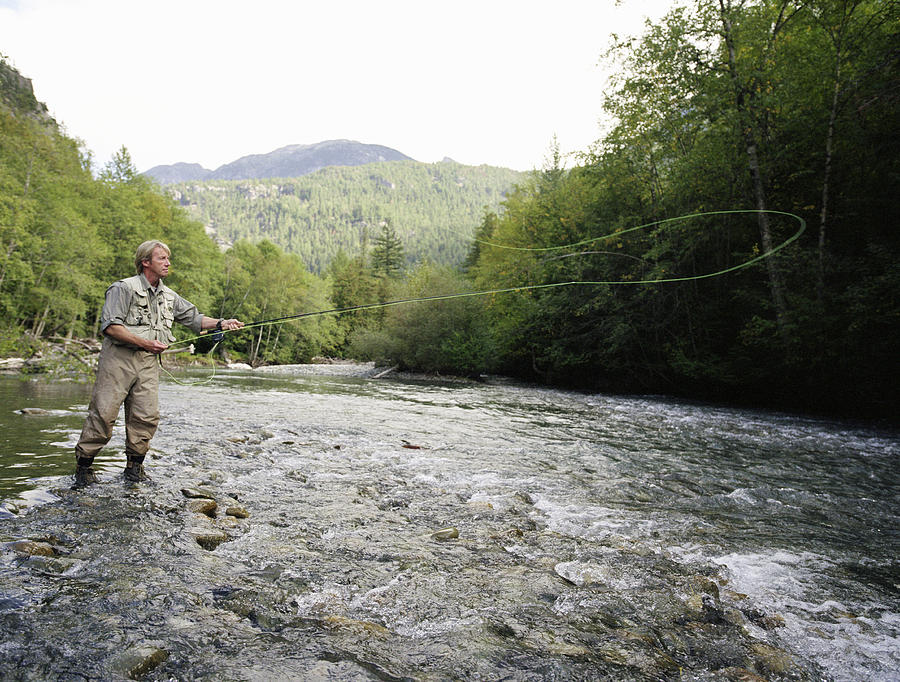 Mature man fly fishing in river, casting line Photograph by Mike Powell