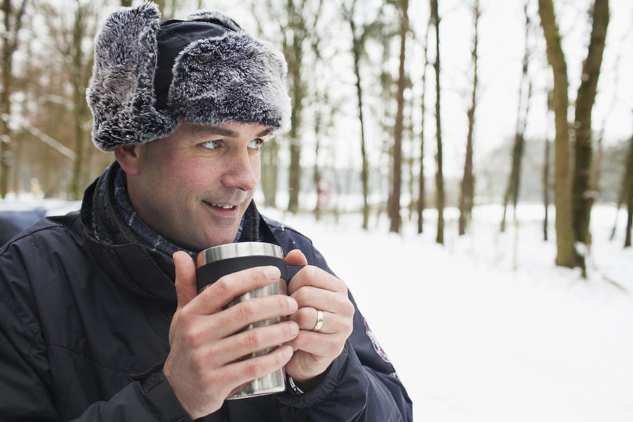 Mature man having hot drink outside in winter Photograph by Frank van Delft