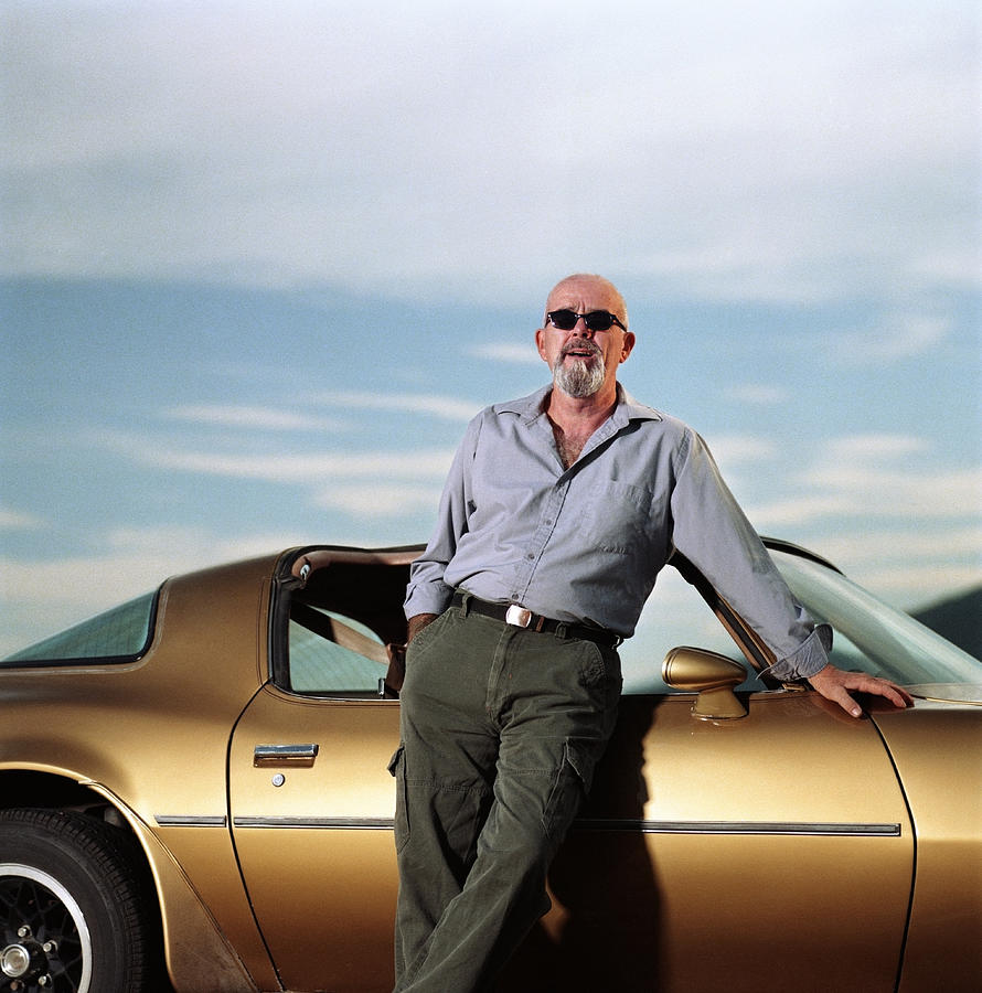 Mature man leaning against sports car, portrait Photograph by Kevin Jordan