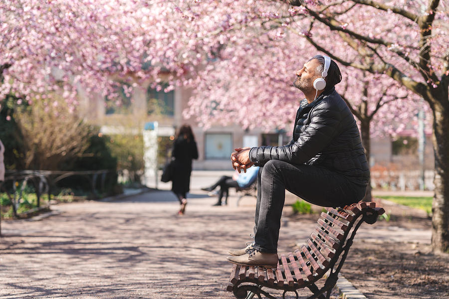 Mature man listening to music in the park Photograph by Luza Studios