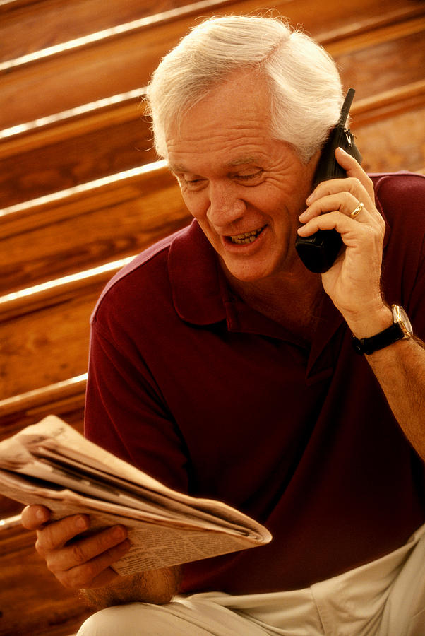Mature Man On Phone With Newspaper Photograph by Yellow Dog Productions