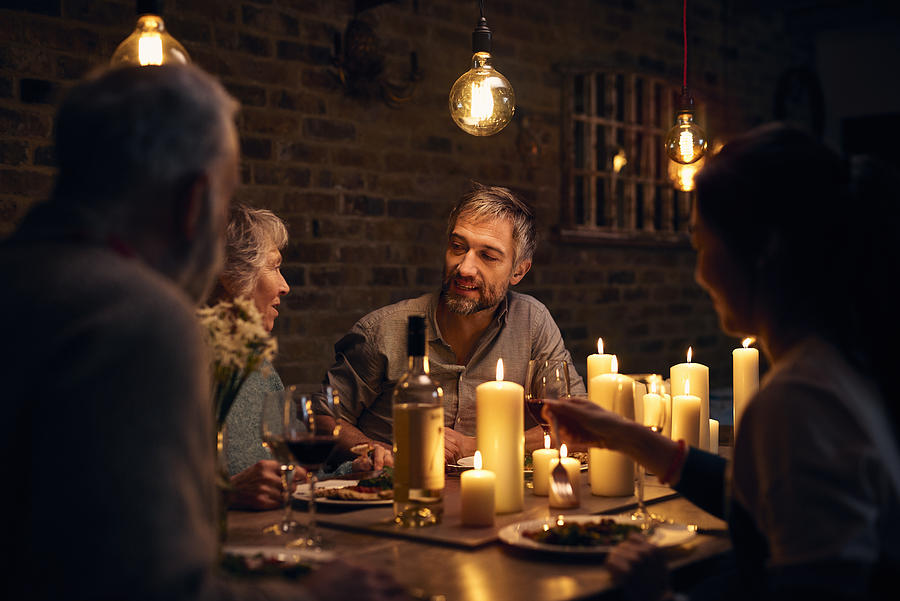 Mature man talking to friends at candlelit dinner table Photograph by 10000 Hours