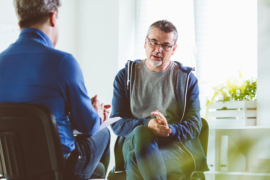 Mature man talking with psychotherapist in his office Photograph by Izusek