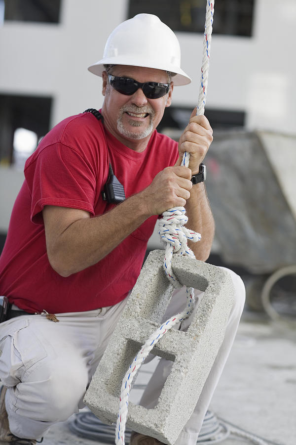 Mature man tightening a rope on a concrete block Photograph by Glowimages
