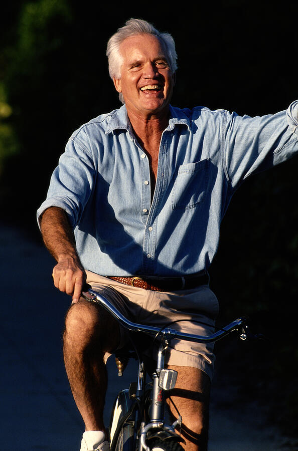 Mature Man Waving On Bicycle Photograph by Yellow Dog Productions