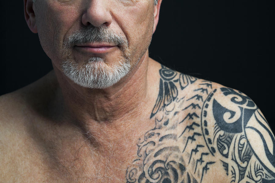 Mature man with tattoo on shoulder, cropped. Photograph by Andreas Kuehn