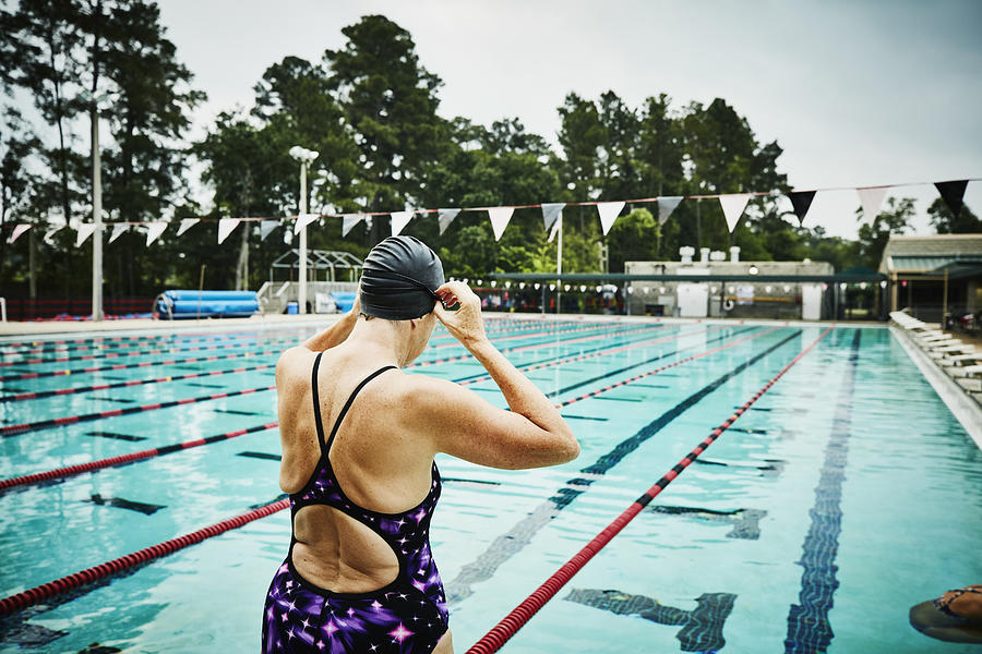 Mature woman adjusting goggles at side of outdoor pool before morning workout Photograph by Thomas Barwick