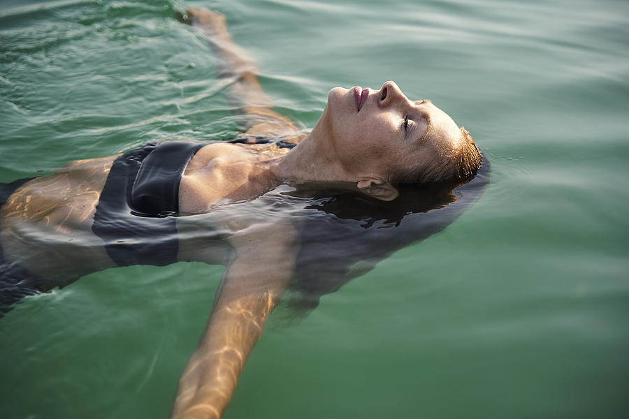 Mature woman floating in a lake with closed eyes Photograph by Westend61