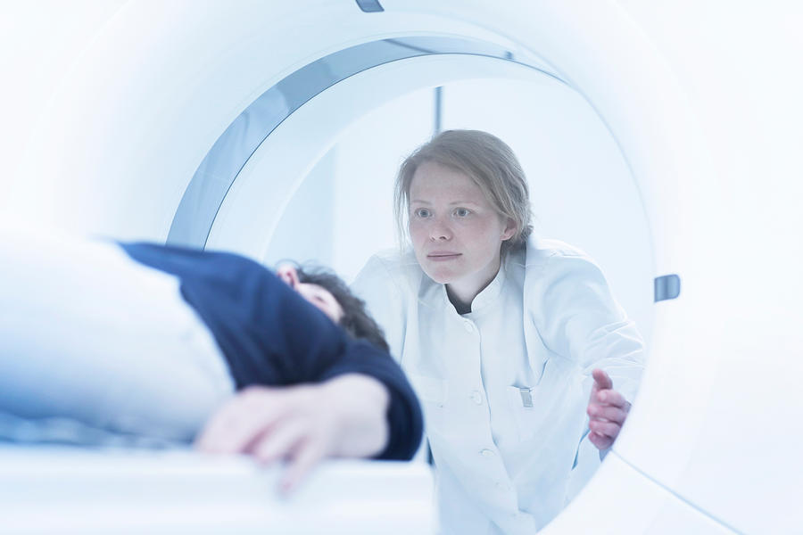 Mature woman having CT scan, radiologist standing beside tunnel Photograph by Sigrid Gombert
