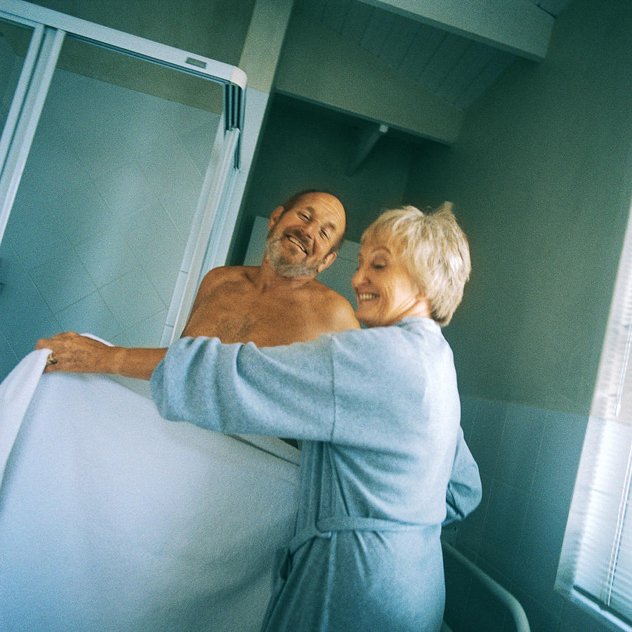 Mature woman holding towel in front of nude man Photograph by Patrick Sheandell OCarroll
