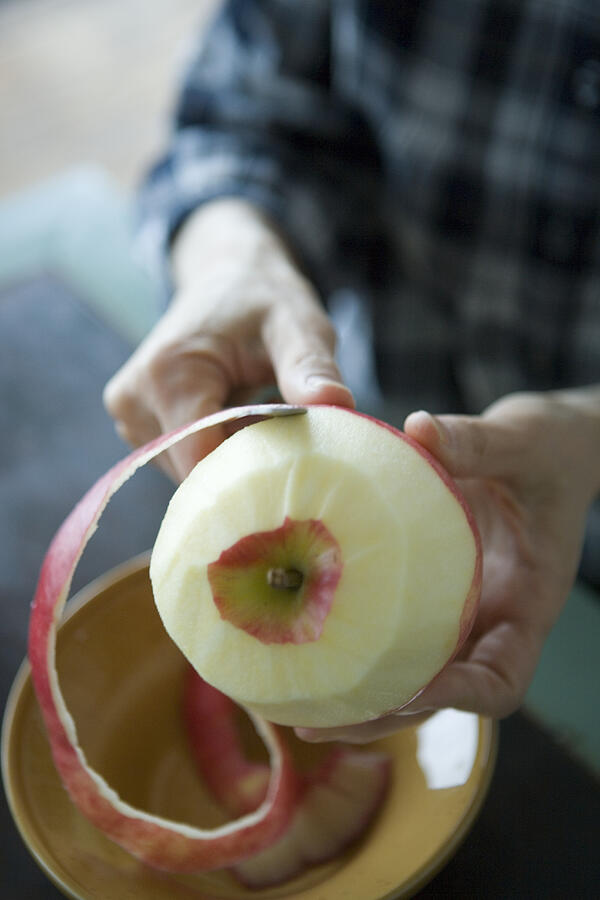 Mature woman peeling apple skin Photograph by Indeed
