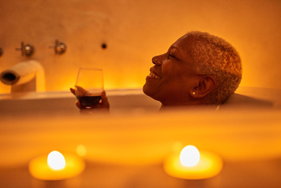 Mature woman relaxes in bath Photograph by Flashpop